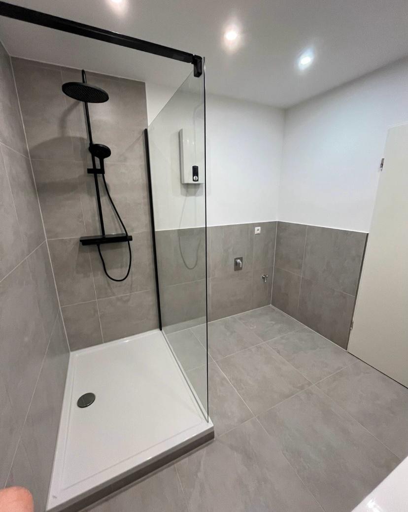 Bodenebene Dusche mit Glasabtrennung und schwarzer Armatur, im Bauzustand